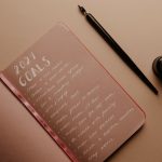 A notebook with '2021 Goals' written in calligraphy, featuring a pen and ink bottle.